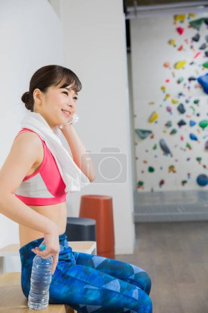 Téléchargez les photos : Femme asiatique grimpeur près mur d'escalade en salle de gym - en image libre de droit