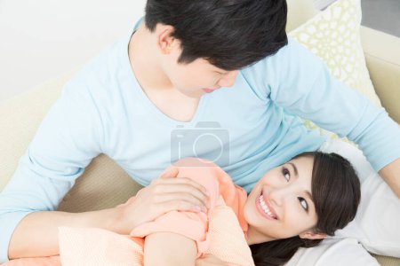 Photo for Young asian family relaxing together on sofa at home - Royalty Free Image