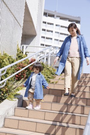 Téléchargez les photos : Portrait de mignon enfant japonais avec mère marchant sur les escaliers à l'extérieur - en image libre de droit