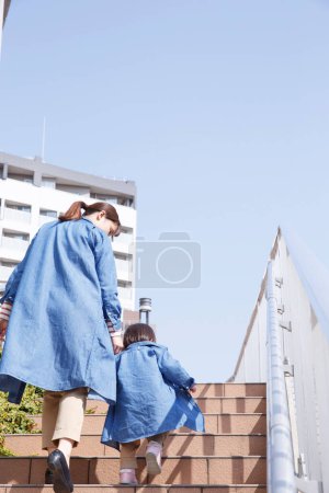 Photo for Portrait of cute Japanese child with mother walking on stairs outdoors - Royalty Free Image
