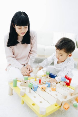 Téléchargez les photos : Mignon japonais garçon jouer avec mère à la maison - en image libre de droit