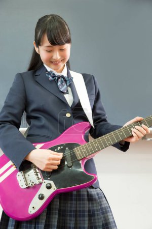 Foto de Asiático adolescente chica jugando guitarra en aula - Imagen libre de derechos