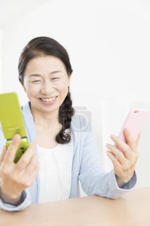 Téléchargez les photos : Gros plan senior asiatique femme comparant deux téléphones - en image libre de droit