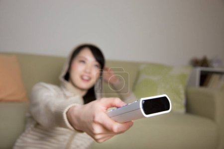 Téléchargez les photos : Asiatique femme avec télécommande regarder la télévision - en image libre de droit