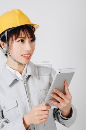 Photo for Young asian woman engineer in helmet holding tablet pc - Royalty Free Image