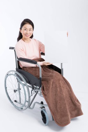 Photo for Asian woman in wheelchair holding a blank banner - Royalty Free Image