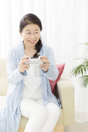 Photo for Asian woman playing video game with gamepad - Royalty Free Image