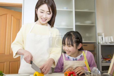Photo for Young mother and daughter preparing fresh salad in kitchen - Royalty Free Image