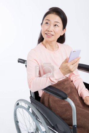 Téléchargez les photos : Femme utilisant un smartphone dans un fauteuil roulant - en image libre de droit