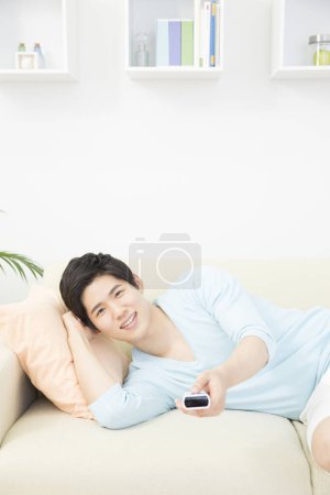 Téléchargez les photos : Femme relaxante sur canapé avec télécommande - en image libre de droit