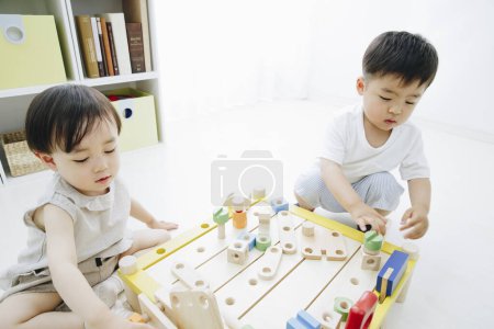Foto de Lindos niños japoneses jugando con juguetes en casa - Imagen libre de derechos