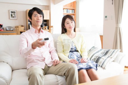 Téléchargez les photos : Asiatique couple regarder la télévision dans salon - en image libre de droit