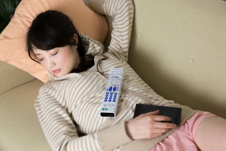 Téléchargez les photos : Femme avec téléphone portable et télécommande dormant sur canapé - en image libre de droit