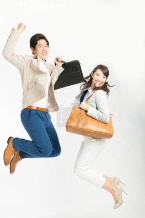 Photo for Asian couple in business clothes jumping, studio shot - Royalty Free Image
