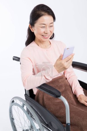 Photo for Asian senior woman  in wheelchair using smartphone  on isolated background - Royalty Free Image