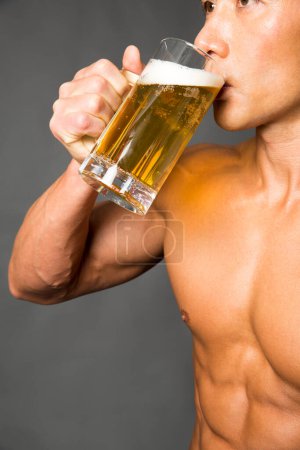 Foto de Retrato de hombre con cuerpo musculoso sosteniendo vaso de cerveza - Imagen libre de derechos
