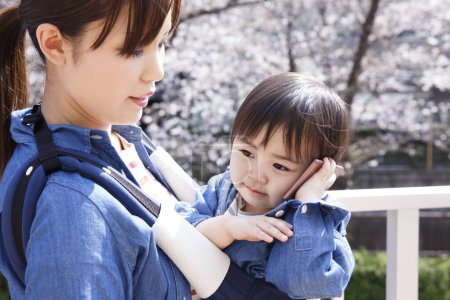 Photo for Portrait of cute Japanese child with mother with smartphone on street - Royalty Free Image