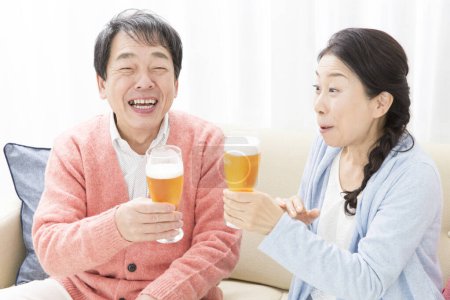 Téléchargez les photos : Couple aîné avec bière à la maison - en image libre de droit