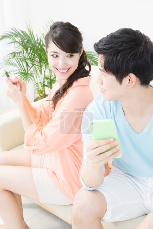 Téléchargez les photos : Couple assis avec des smartphones sur le canapé - en image libre de droit