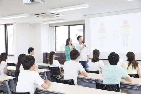Téléchargez les photos : Étudiants asiatiques avec microphones faisant la présentation pendant la leçon - en image libre de droit