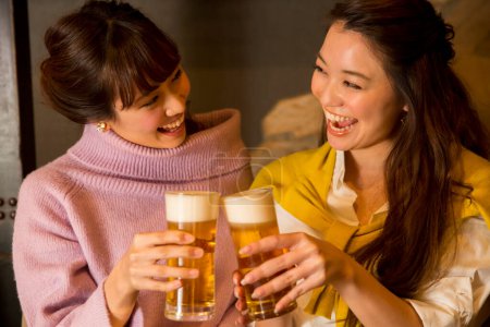 Téléchargez les photos : Deux jeunes femmes asiatiques s'amuser ensemble au restaurant avec de la bière - en image libre de droit