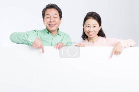 Foto de Asiático senior pareja sonriendo y apuntando blanco tarjeta - Imagen libre de derechos