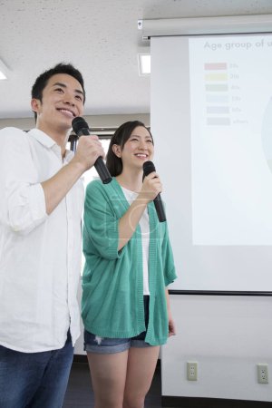 Téléchargez les photos : Étudiants asiatiques avec microphones faisant la présentation pendant la leçon - en image libre de droit