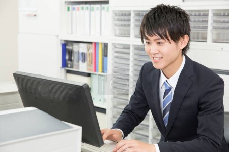 Foto de Joven asiático hombre de negocios trabajando en la computadora en oficina - Imagen libre de derechos