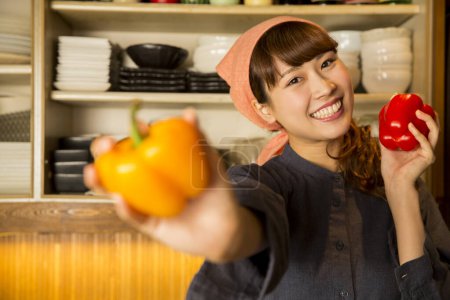 Téléchargez les photos : Femme asiatique avec poivron orange dans la cuisine - en image libre de droit