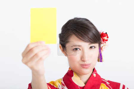 Foto de Mujer usando japonés kimono celebración amarillo tarjeta en blanco - Imagen libre de derechos