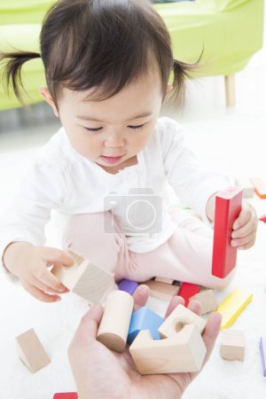 Téléchargez les photos : Asiatique enfant fille jouer avec coloré jouet blocs sur le sol dans maternelle - en image libre de droit