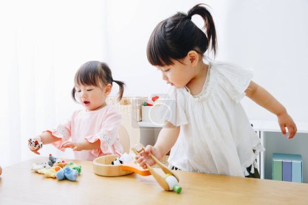 Photo for Closeup shot of cute Japanese girls playing with toys at home interior - Royalty Free Image