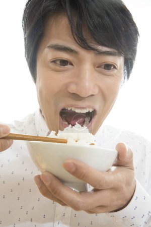 Téléchargez les photos : Asiatique japonais l'homme avec baguettes manger riz - en image libre de droit