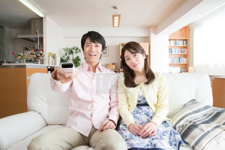Foto de Feliz pareja usando control remoto en casa - Imagen libre de derechos