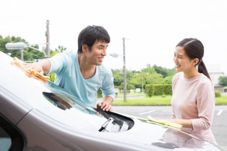 Foto de Sonriente japonés pareja lavado coche en calle - Imagen libre de derechos