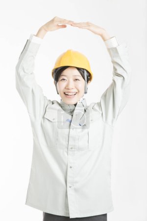 Téléchargez les photos : Portrait de belle jeune femme japonaise en casque de sécurité posant sur fond de studio blanc - en image libre de droit