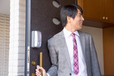 Foto de Joven hombre de negocios japonés en traje saliendo de casa - Imagen libre de derechos