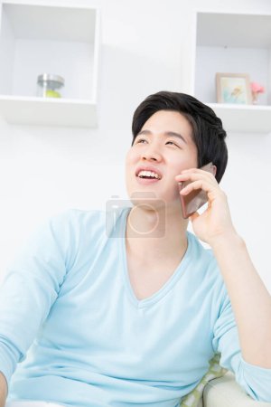 Foto de Asiático hombre con smartphone en casa - Imagen libre de derechos