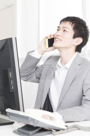 Foto de Primer plano retrato de un joven empresario japonés hablando por teléfono en la oficina - Imagen libre de derechos