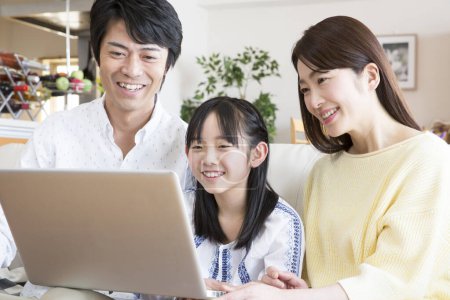 Téléchargez les photos : Heureuse famille asiatique avec ordinateur portable sur canapé - en image libre de droit