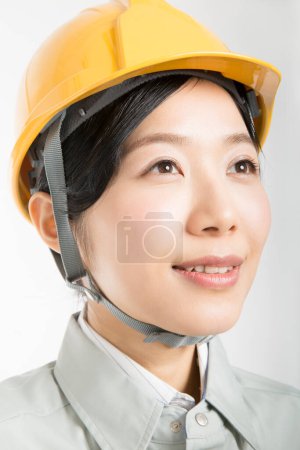 Photo for Portrait of beautiful young Japanese woman in safety helmet posing over white studio background - Royalty Free Image