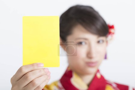 Téléchargez les photos : Femme portant kimono japonais tenant carton jaune carte blanche - en image libre de droit