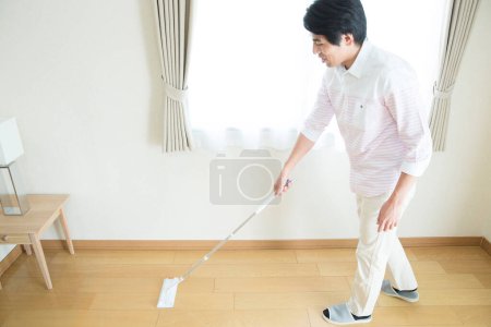 Téléchargez les photos : Asiatique homme nettoyage son maison avec balai - en image libre de droit