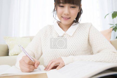 Foto de Potrait de hermosa japonesa adolescente chica doign tarea en casa - Imagen libre de derechos