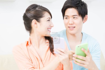 Photo for Young couple using mobile phones together at home - Royalty Free Image