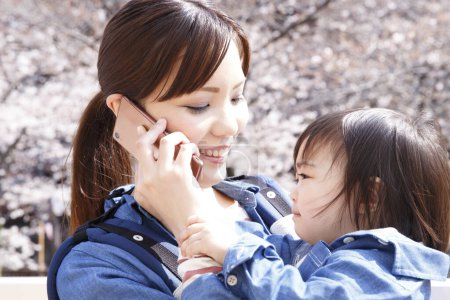 Photo for Portrait of cute Japanese child with mother with smartphone on street - Royalty Free Image