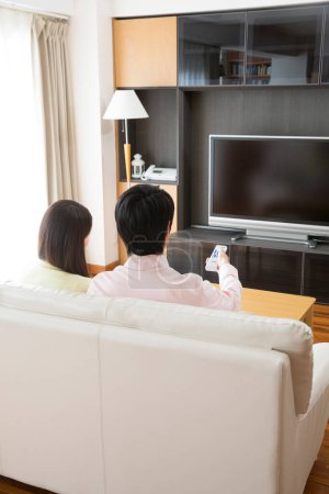 Téléchargez les photos : Asiatique couple regarder tv à la maison - en image libre de droit