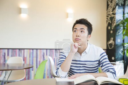 Photo for Asian student studying at table in college - Royalty Free Image