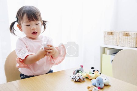 Photo for Closeup shot of cute Japanese girl playing with toys at home interior - Royalty Free Image