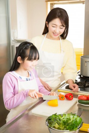 Photo for Young mother with daughter cooking - Royalty Free Image